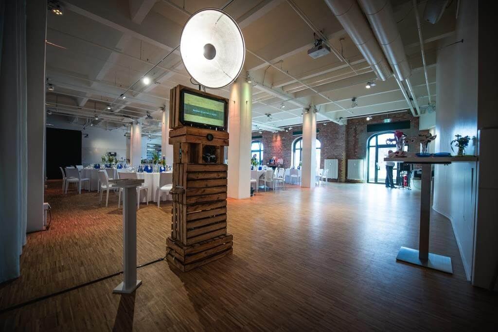 The wooden photo booth with studio flash set up in an event venue with dressed tables